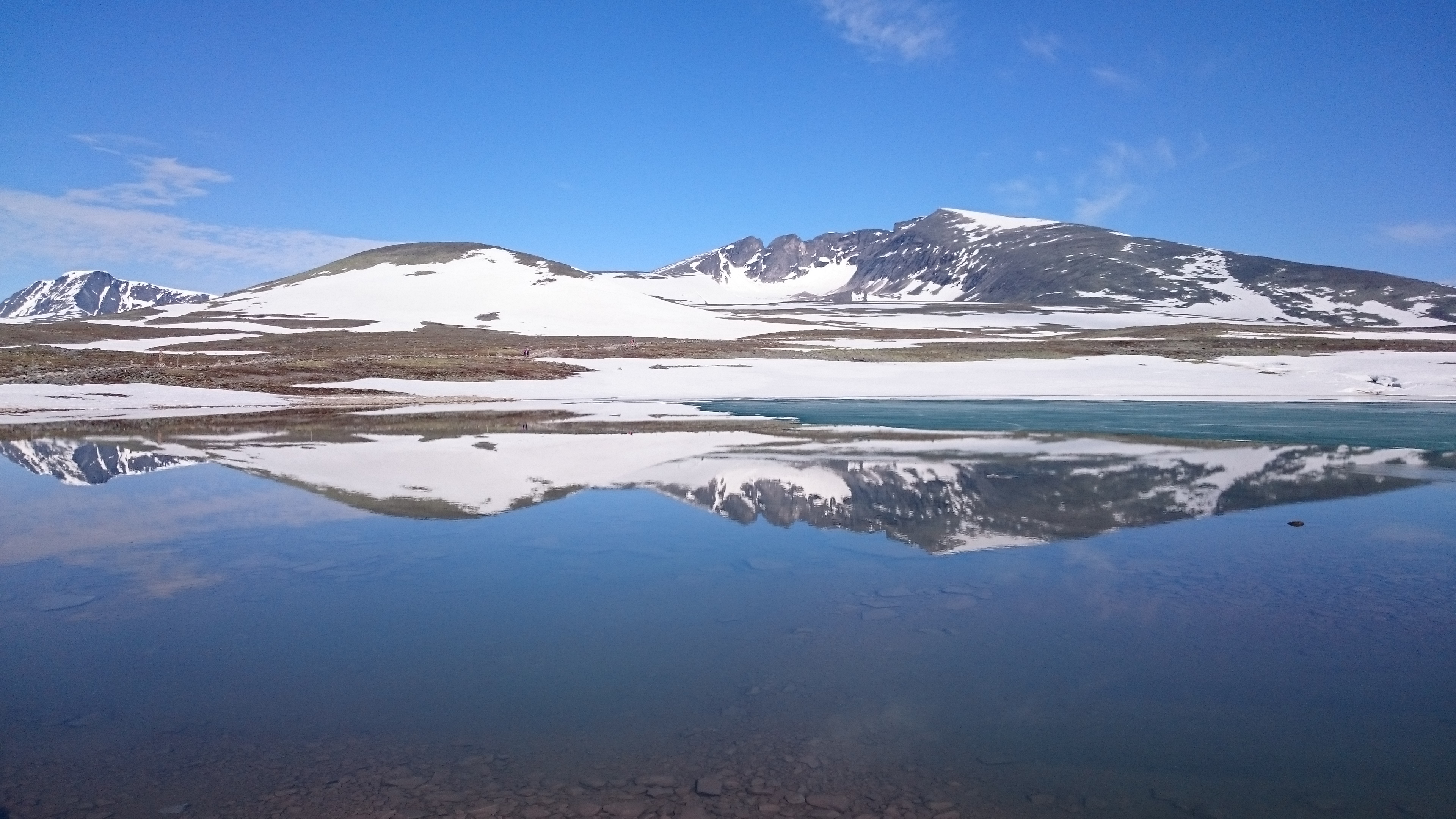 Snøkledt fjell som speiler seg i stille vannvann