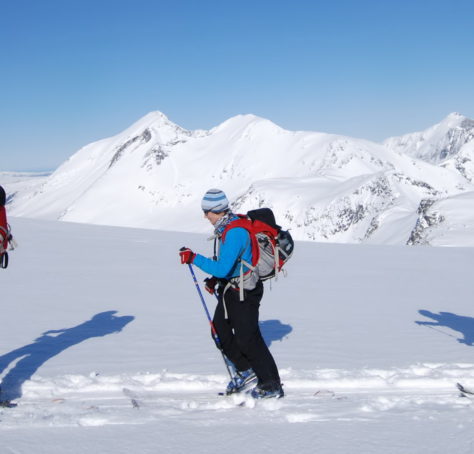 Tre skiløpere (rando) foran alpine fjell