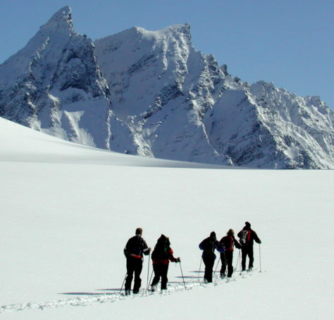Skiløpere på snøflate foran alpint fjell