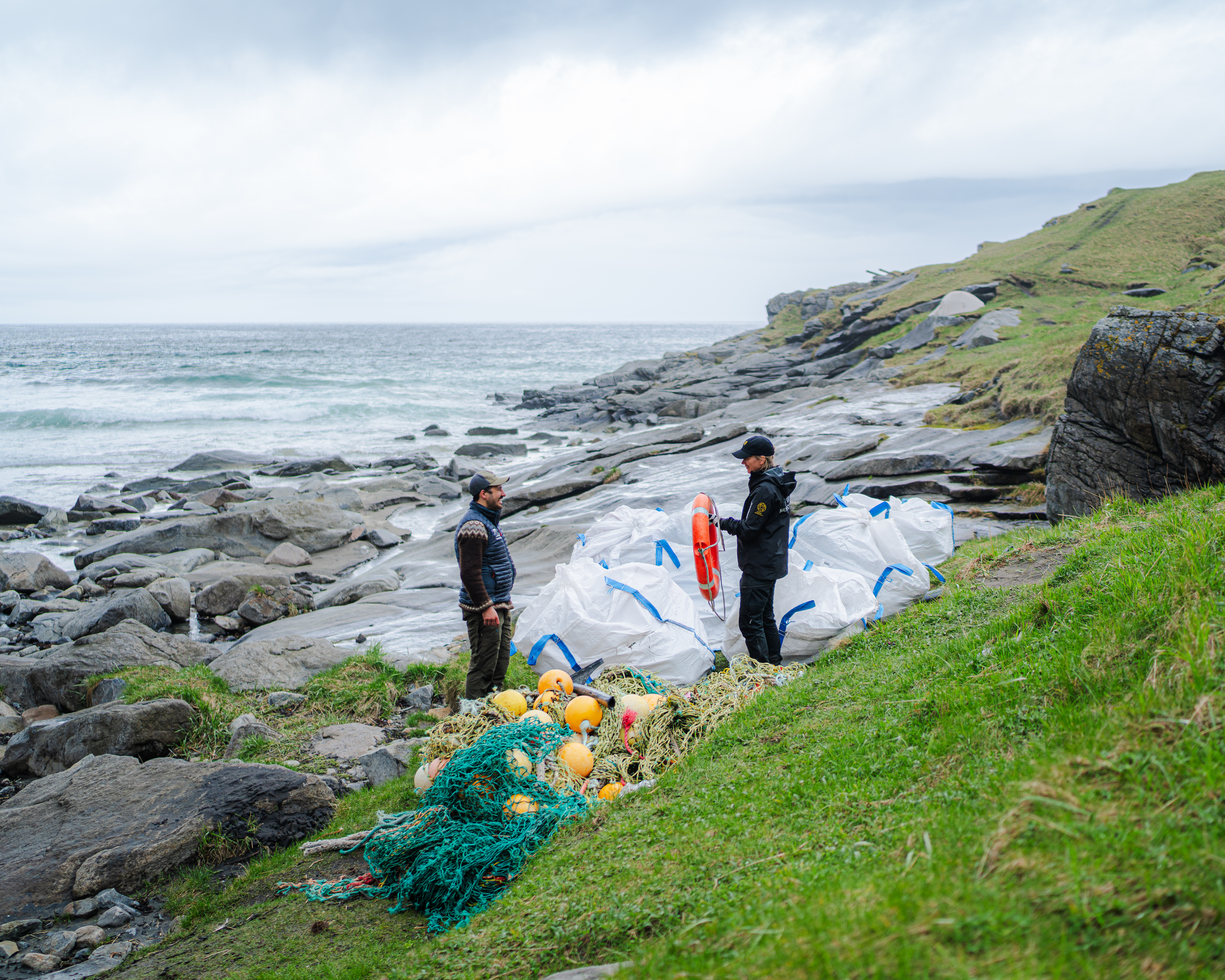 Mann og kvinne ser over haugen med marint avfall som er samlet sammen. Hun har funnet en livbøye som har vasket i land.
